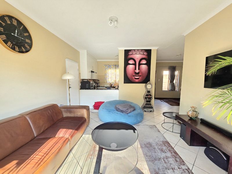 Open plan living area featuring tiled flooring, neutral wall tones, and a functional kitchen layout with built-in cabinetry and an extractor fan.