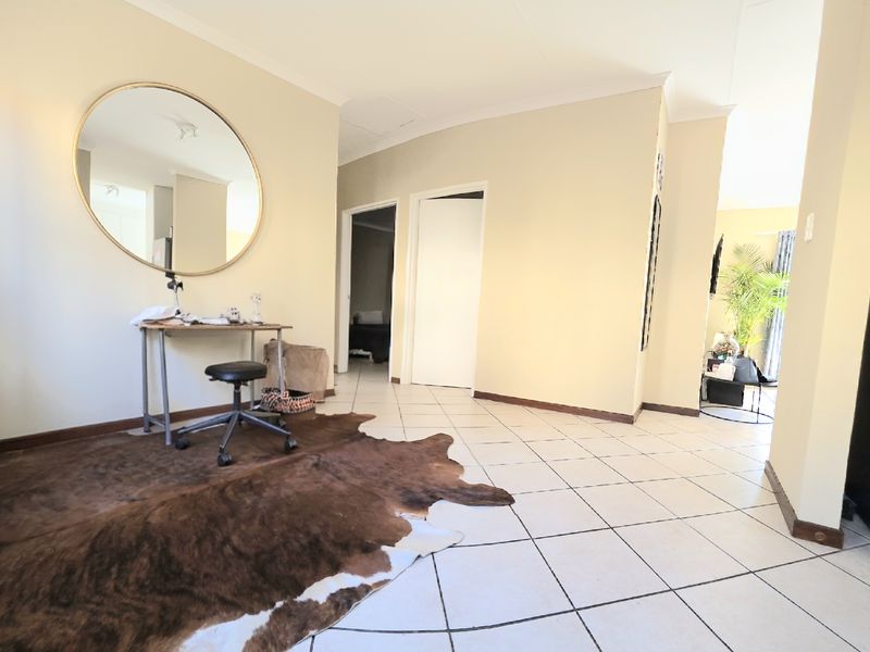 A bright, open-plan living area featuring neutral wall tones and ceramic floor tiles, providing a versatile space with access to adjacent rooms.