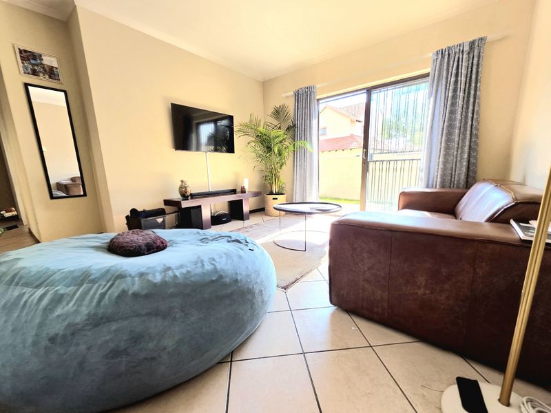A comfortable living room featuring tiled flooring and large sliding glass doors that provide direct access to the outdoor patio area.