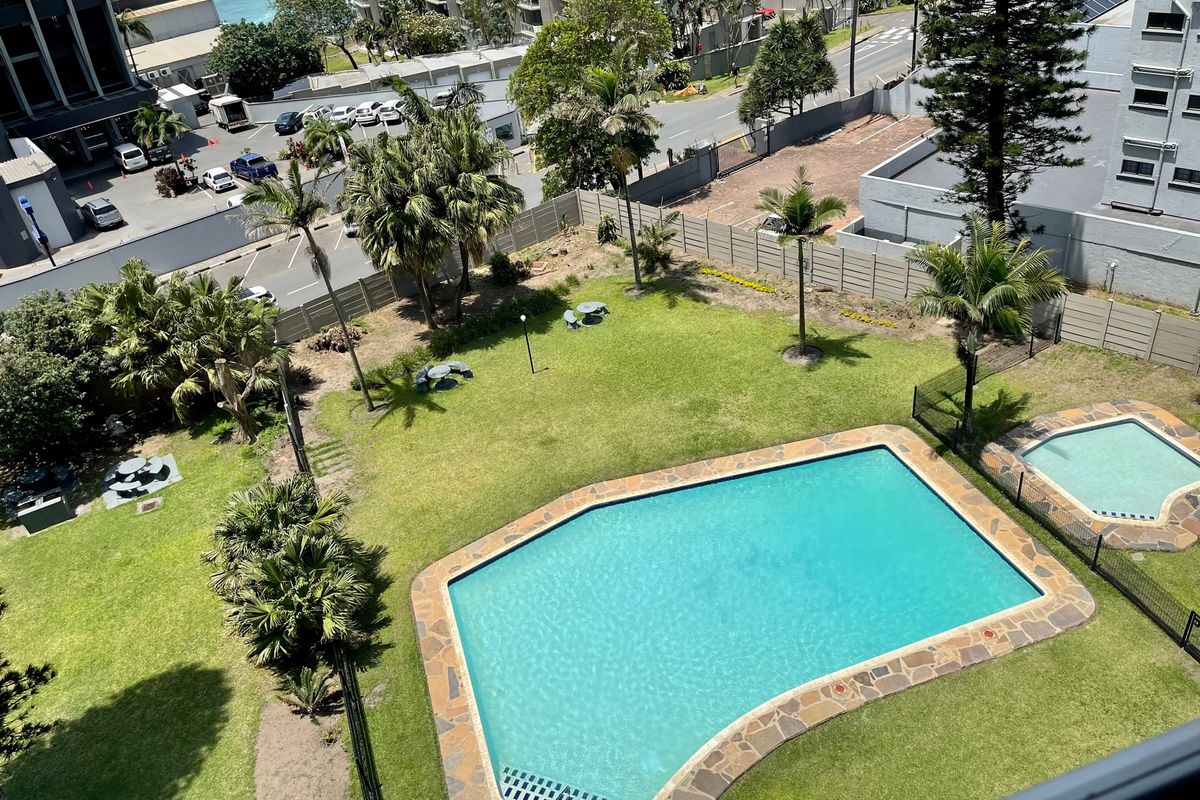Aerial view of a communal garden area featuring a swimming pool, wading pool, and landscaped lawn within an apartment complex.