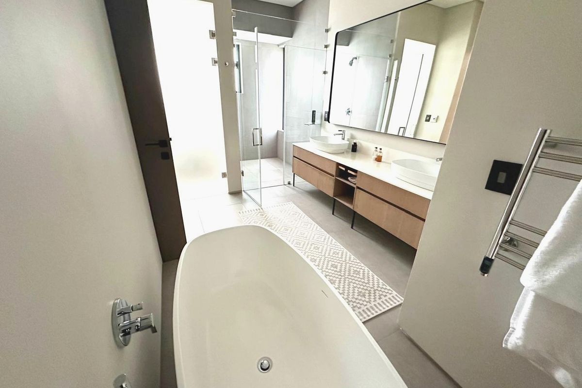 Modern bathroom featuring a freestanding bathtub, double vanity with vessel sinks, large wall mirror, and a glass-enclosed walk-in shower.