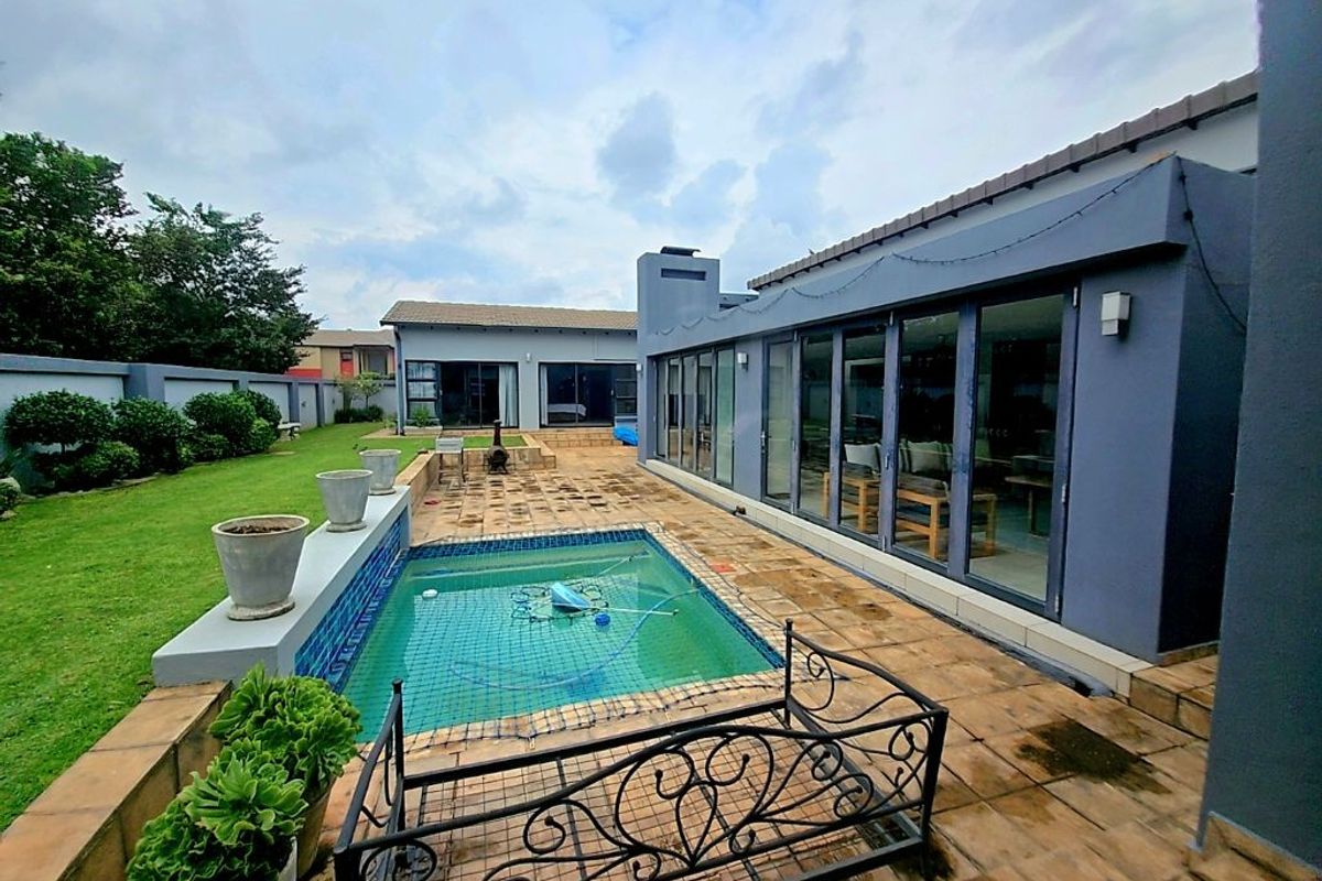 Spacious rear garden featuring a swimming pool, paved patio area, and large glass sliding doors providing seamless indoor-outdoor flow.