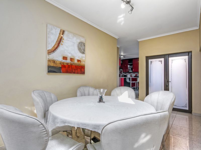 A dining room featuring tiled flooring and a frosted glass panel door, with a view through to the kitchen area.