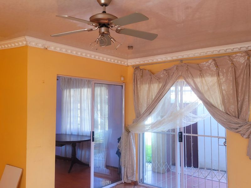 Living room featuring crown molding, a ceiling fan, and sliding glass doors providing access to an outdoor area.