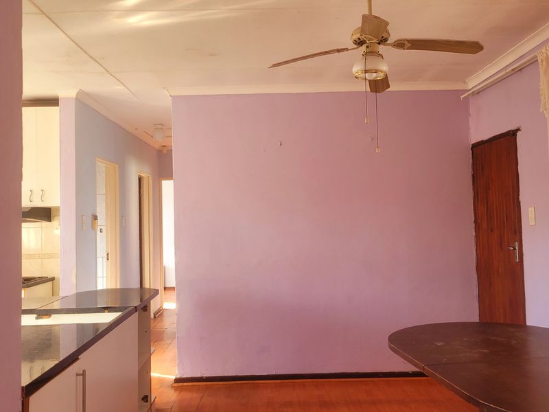 Open plan living and kitchen area featuring laminate flooring, a ceiling fan, and direct access to internal hallways.