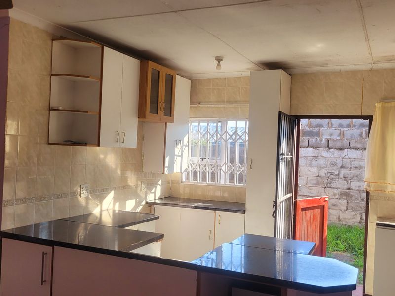 A functional kitchen space featuring built-in cabinetry, dark countertops, and direct access to the rear exterior, offering potential for modernization and cosmetic updates.