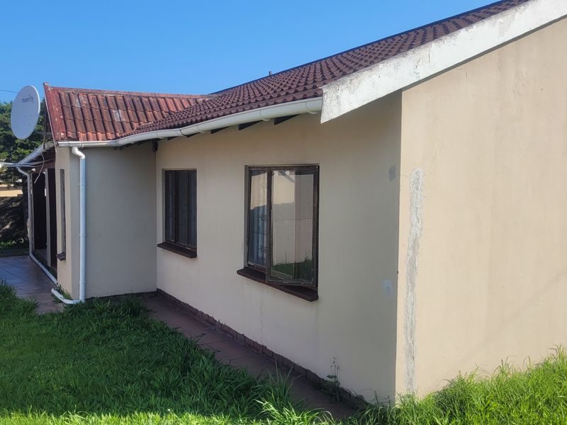 Rear exterior view of the property featuring a tiled roof, gutter system, and exterior wall surfaces requiring maintenance and painting.