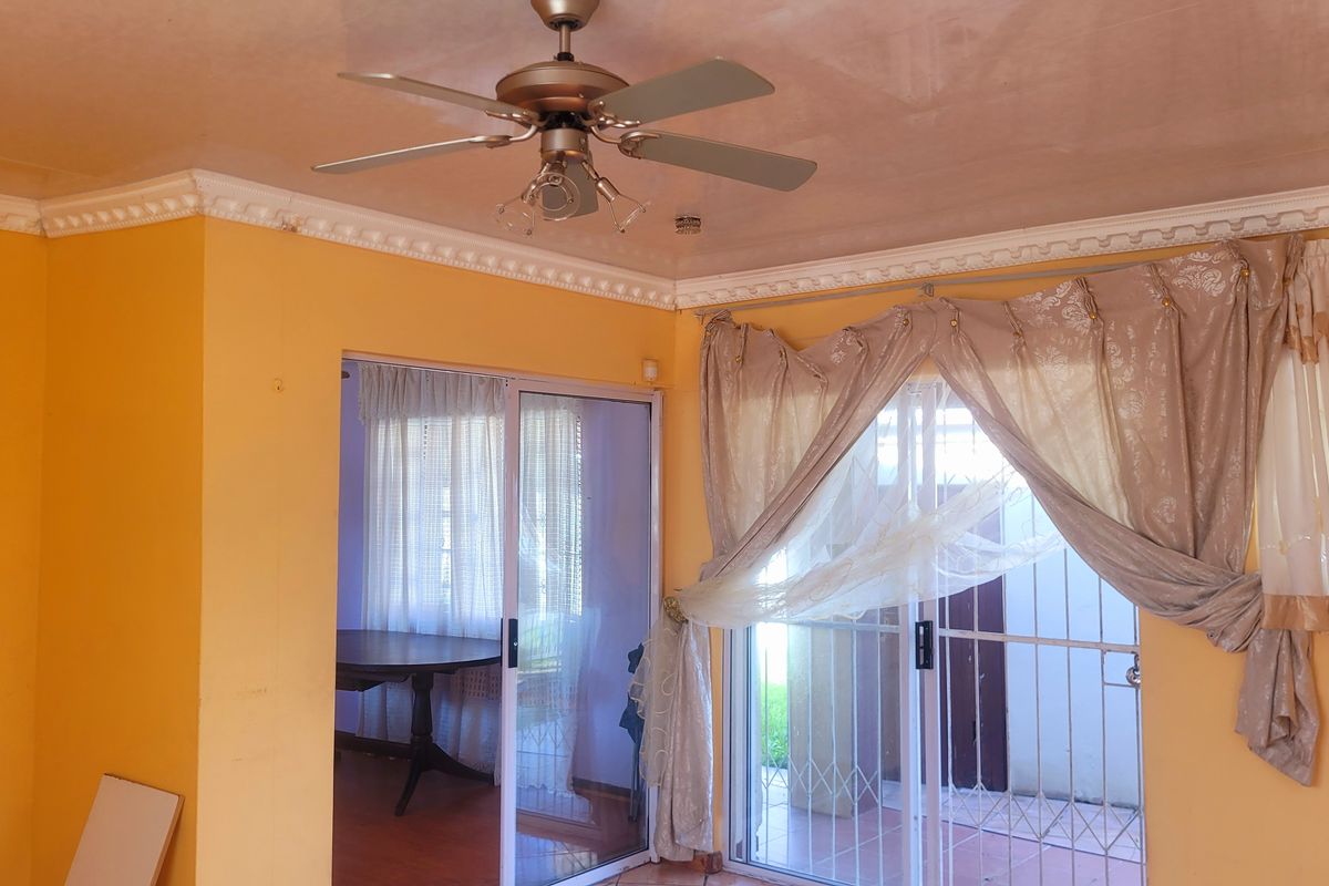 Living room featuring crown molding, a ceiling fan, and sliding glass doors providing access to an outdoor area.