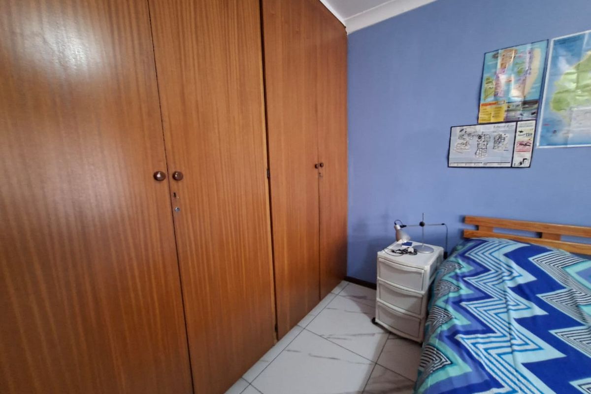 A bedroom featuring built-in wooden cupboards, tiled flooring, and blue painted walls.