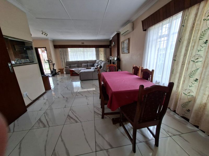 Spacious open-plan living and dining area featuring polished marble-look floor tiles, coved ceilings, and a wall-mounted air conditioning unit.