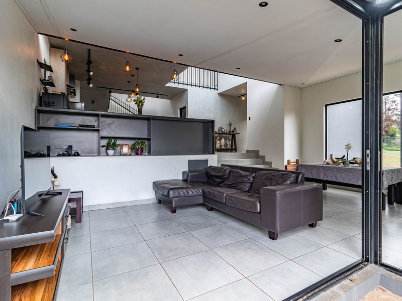Spacious open-plan living area featuring modern tiled floors, built-in shelving, and seamless indoor-outdoor flow through large sliding glass doors.