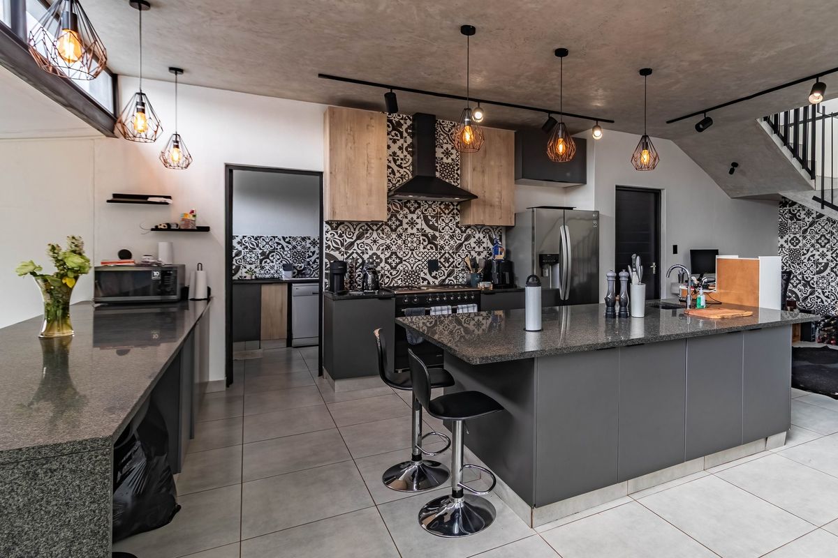 Modern open-plan kitchen featuring granite countertops, a central island, patterned tile backsplash, and high-end built-in cabinetry with integrated lighting.