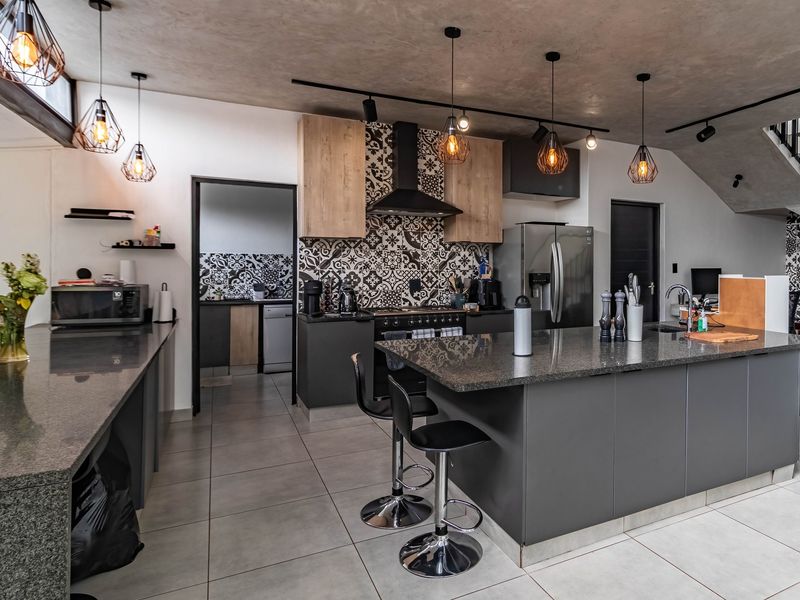 Modern open-plan kitchen featuring granite countertops, a central island, patterned tile backsplash, and high-end built-in cabinetry with integrated lighting.