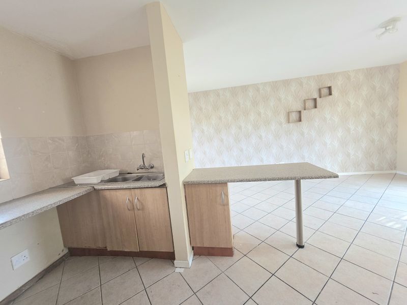 Open plan kitchen and living area featuring tiled flooring, a breakfast bar, and built-in cabinetry with laminate countertops.