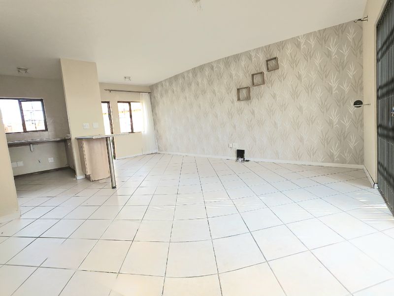 Spacious open-plan living area featuring tiled flooring, a breakfast bar, and a sliding glass door leading to the outdoor space.