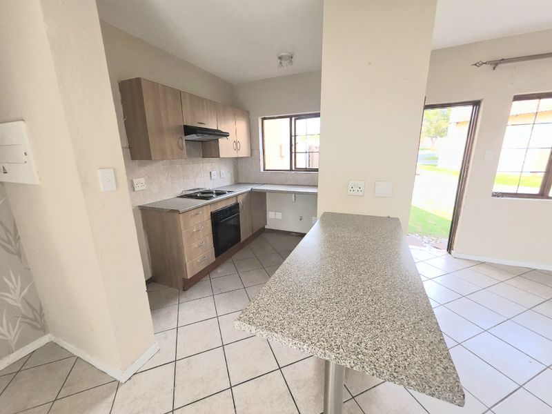 A functional kitchen featuring built-in cabinetry, a breakfast bar, and integrated appliances, with direct access to the exterior.