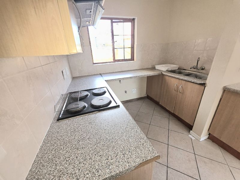 A functional kitchen featuring built-in cabinetry, laminate countertops, an electric hob with extractor fan, and a double bowl sink.