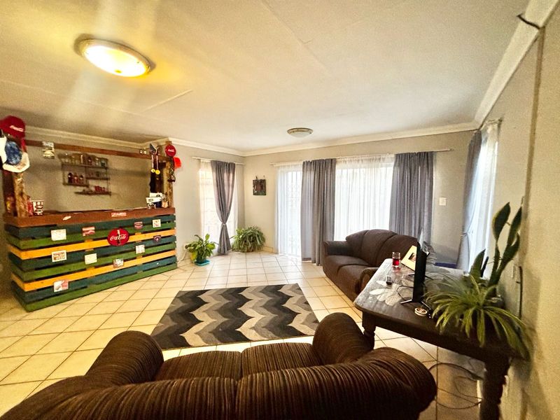 Spacious living room featuring tiled flooring, sliding glass doors for natural light, and a built-in bar area.
