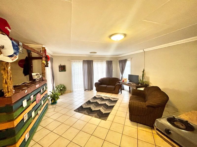 Spacious living area featuring neutral tiled flooring, coved cornicing, and large sliding glass doors providing natural light and access to the exterior.