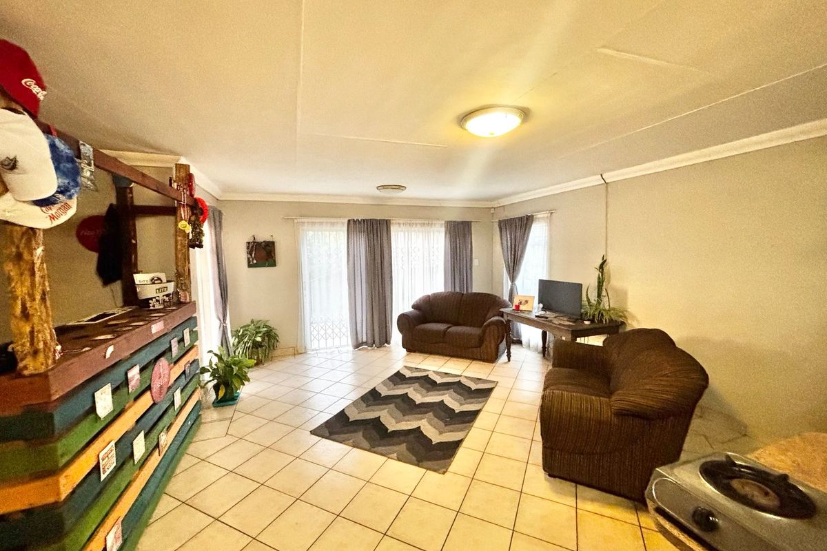 Spacious living area featuring neutral tiled flooring, coved cornicing, and large sliding glass doors providing natural light and access to the exterior.