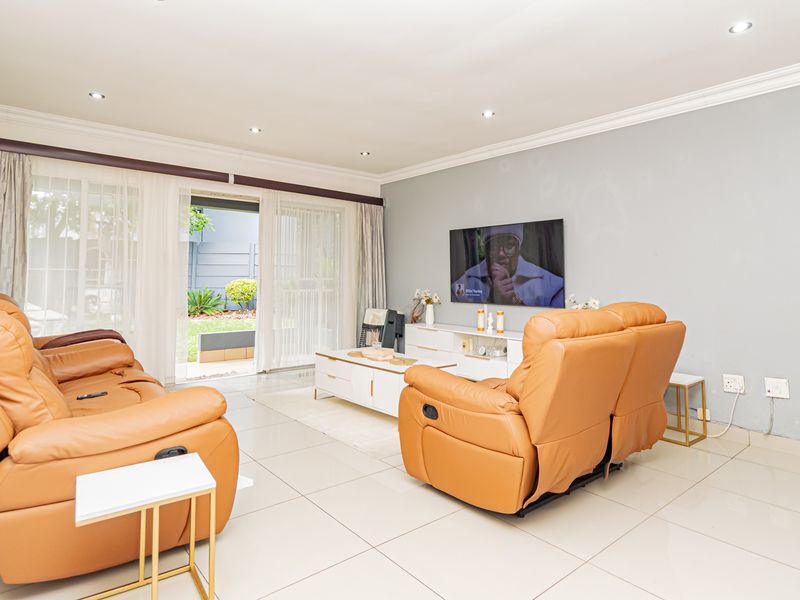 Spacious living room featuring tiled flooring, recessed downlights, and large sliding glass doors providing direct access to the outdoor patio area.