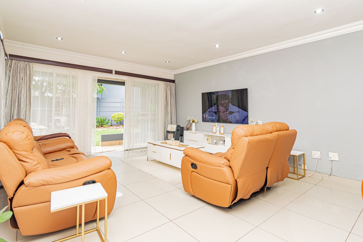 Spacious living room featuring tiled flooring, recessed downlights, and large sliding glass doors providing direct access to the outdoor patio area.