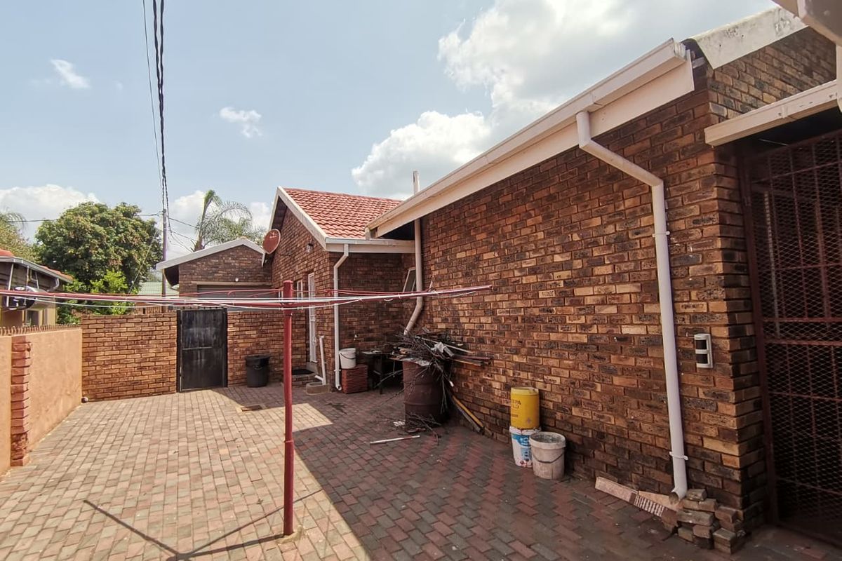 A rear exterior view of the property featuring face brick walls, paved courtyard area, and functional guttering systems.