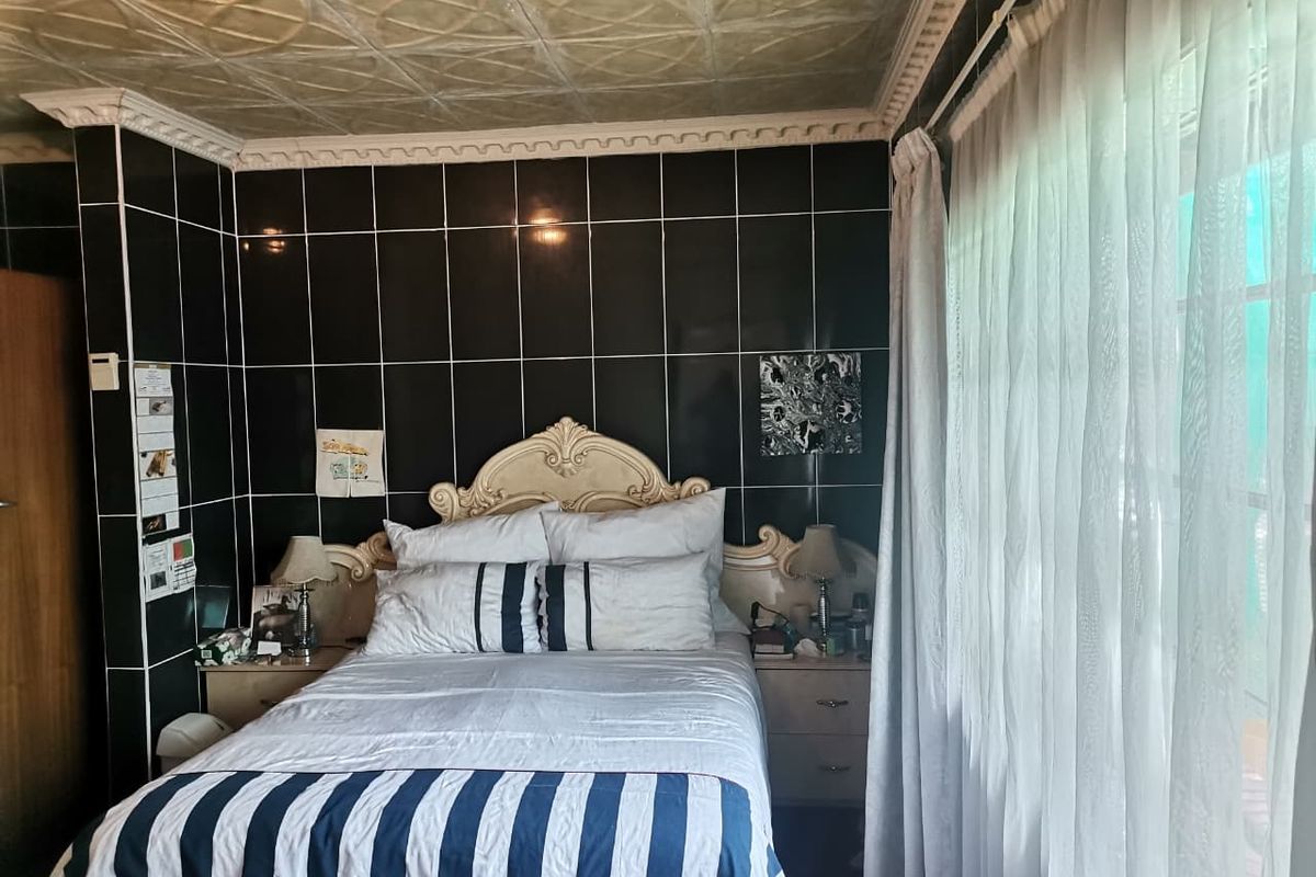 Bedroom featuring dark wall tiles and decorative ceiling panels, offering a unique aesthetic that could be updated for a more modern look.