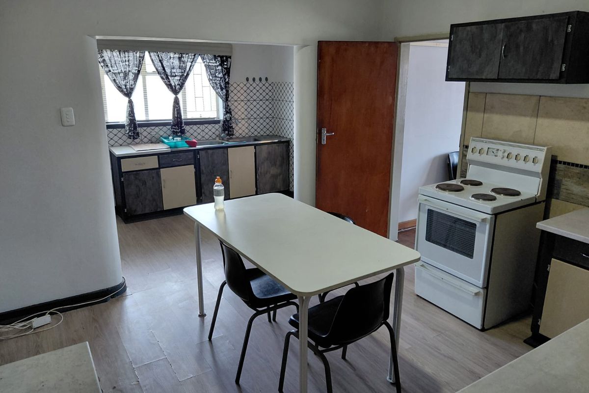 A functional kitchen area featuring built-in cabinetry, a freestanding stove, and a dedicated dining space with laminate flooring.
