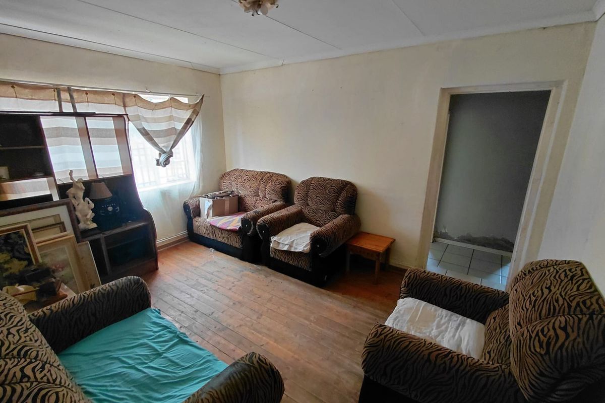 A living room featuring original timber flooring and neutral walls, requiring cosmetic updates to modernize the space.