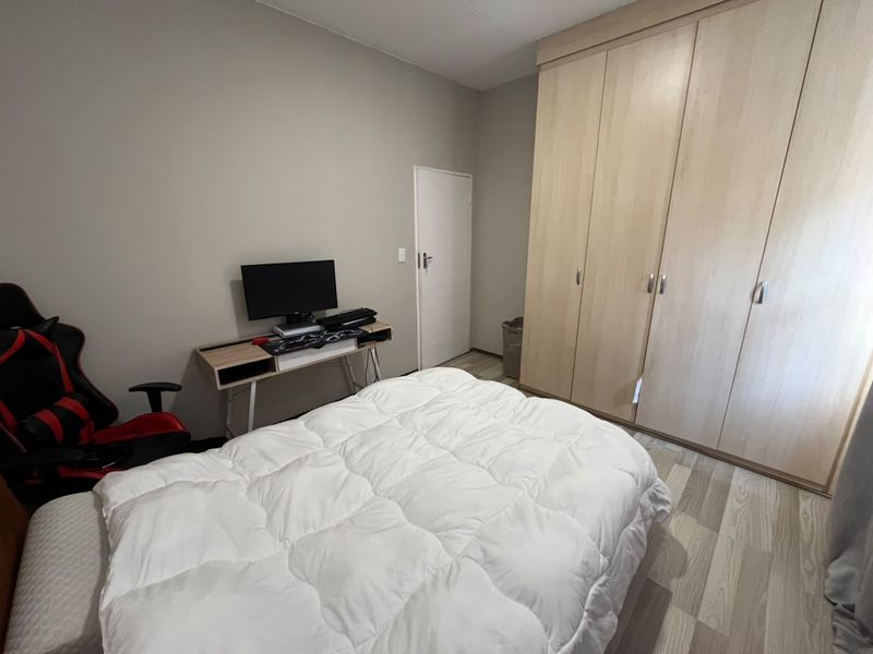 A well-maintained bedroom featuring light wood-tone built-in cupboards and modern laminate flooring, providing a clean and functional living space.