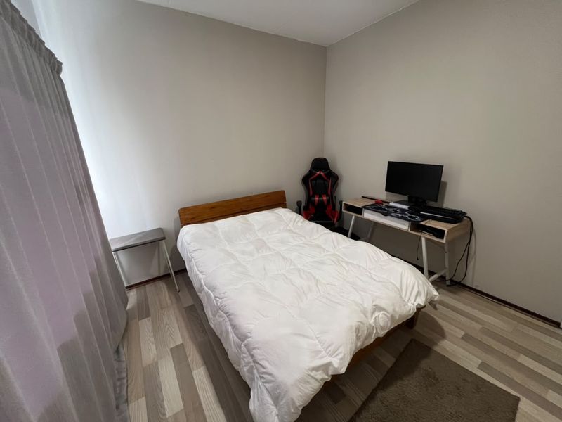 A functional bedroom featuring light-toned laminate flooring and neutral wall finishes, providing a versatile space for rest or study.
