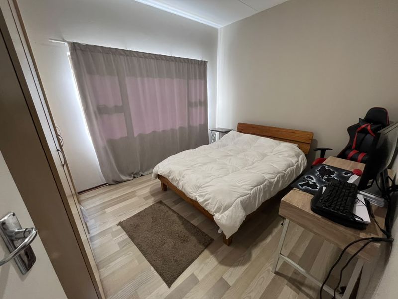 A functional bedroom featuring light-toned laminate flooring and a built-in wardrobe, offering a neutral canvas for personalization.