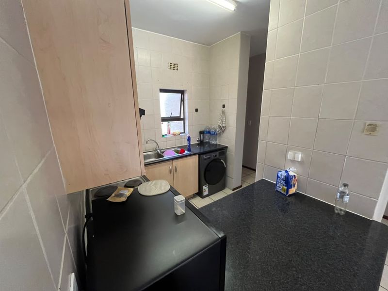 A functional kitchen featuring granite countertops, built-in cabinetry, tiled walls, and integrated plumbing for a washing machine.