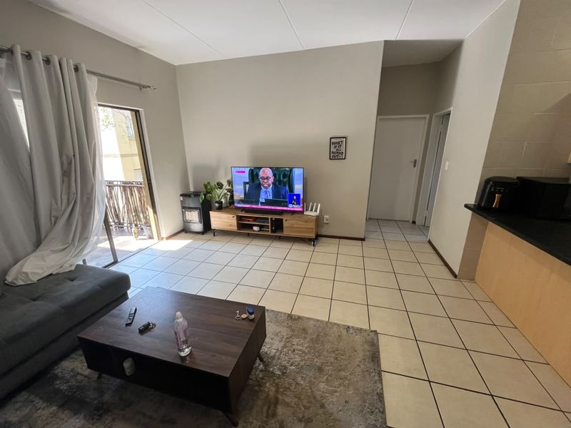 Open-plan living area featuring ceramic tiled flooring, a sliding door leading to a balcony, and an adjacent kitchen counter space.