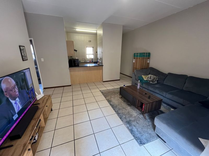 Open plan living area featuring tiled flooring and a functional kitchen with built-in cabinetry and counter space.