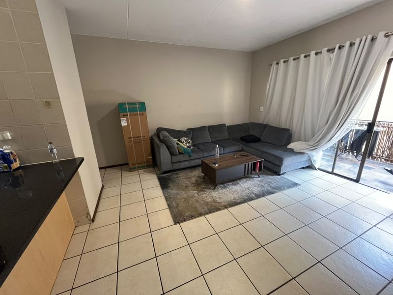 Open plan living area featuring tiled flooring, a granite kitchen counter, and sliding glass doors leading to an outdoor balcony.