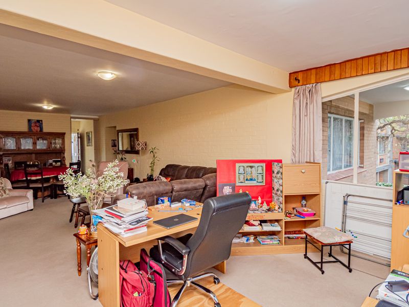 Spacious open-plan living and dining area featuring neutral walls, carpeted flooring, and large windows providing natural light.