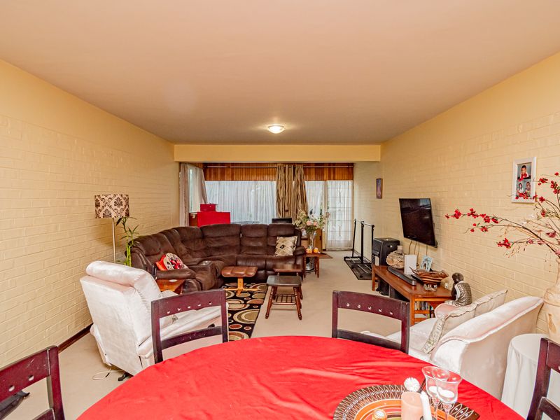Spacious open-plan living and dining area featuring painted brick walls and large sliding glass doors providing natural light.