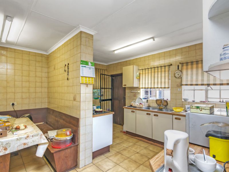 A dated kitchen featuring original tiled walls, built-in cabinetry, and a dedicated dining nook with built-in bench seating.