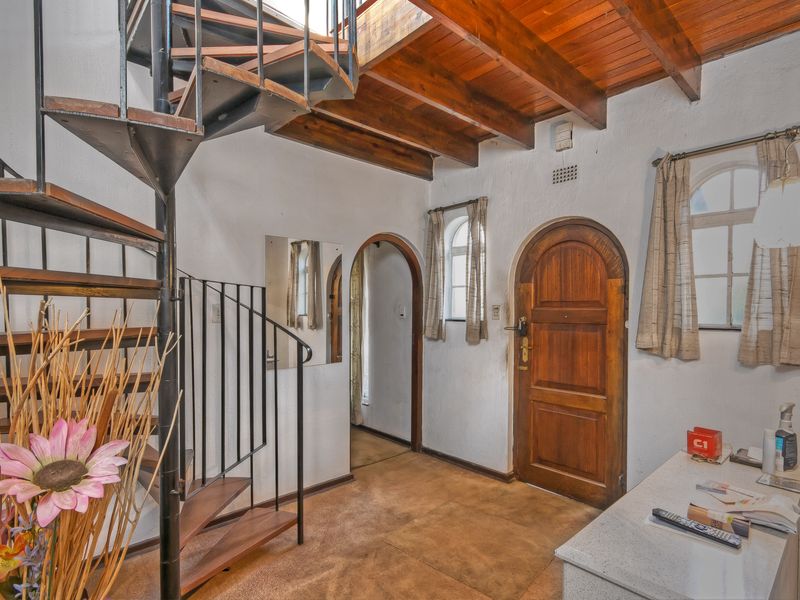 Entrance hall featuring a spiral staircase, exposed timber ceiling beams, and an arched timber front door with tiled flooring.