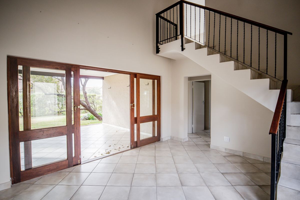 Spacious open-plan living area featuring a staircase with wrought iron balustrade and large sliding doors providing direct access to the outdoor patio.