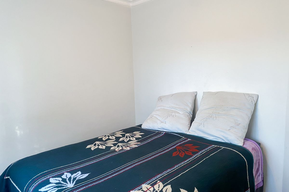 A simple bedroom space featuring plain white walls and decorative ceiling cornicing.