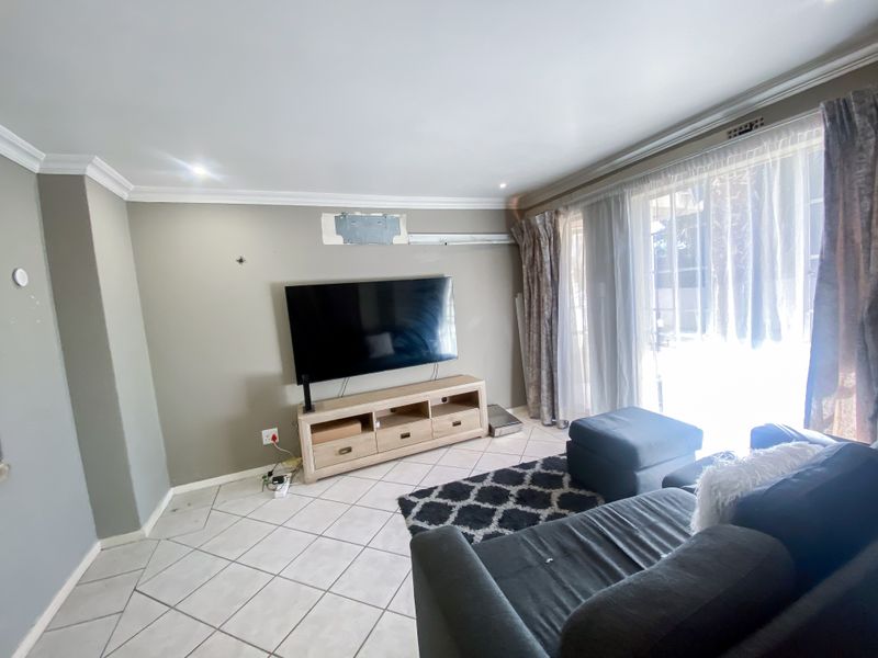 Living room featuring tiled flooring, recessed lighting, and a sliding glass door leading to an outdoor area, with wall-mounted television infrastructure.