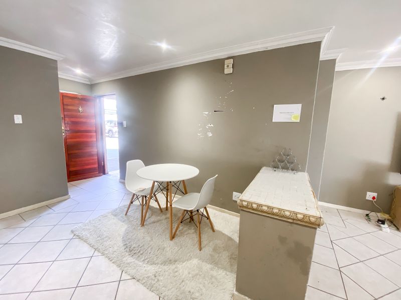 An entry area featuring tiled flooring, coving, and a timber front door, with neutral wall tones and recessed lighting.