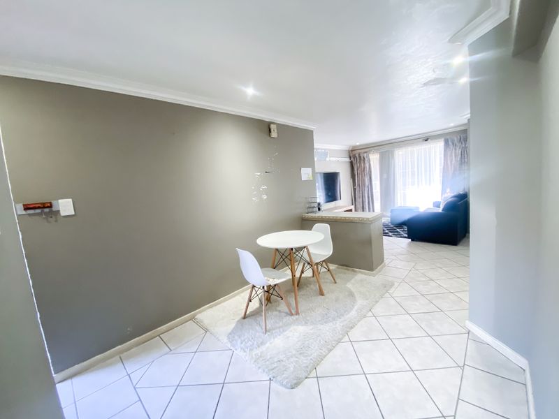Open-plan living and dining area featuring tiled flooring, recessed lighting, and a partition wall, offering a functional layout for modern apartment living.