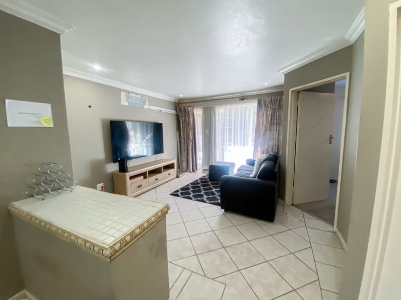 A living room featuring tiled flooring, crown molding, and a sliding glass door leading to an outdoor area.