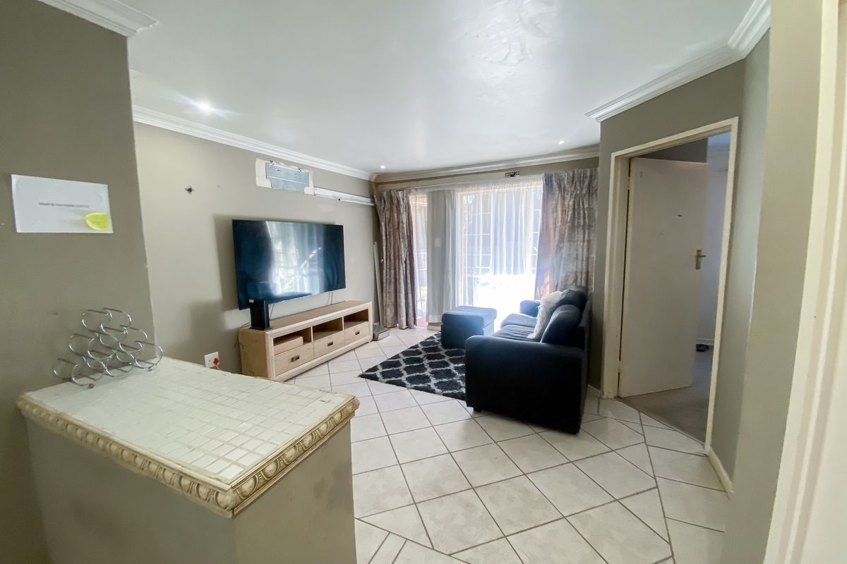 A living room featuring tiled flooring, crown molding, and a sliding glass door leading to an outdoor area.