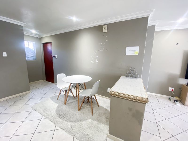 A living area featuring tiled flooring, crown molding, and a built-in counter, currently showing signs of wear on the wall surfaces.