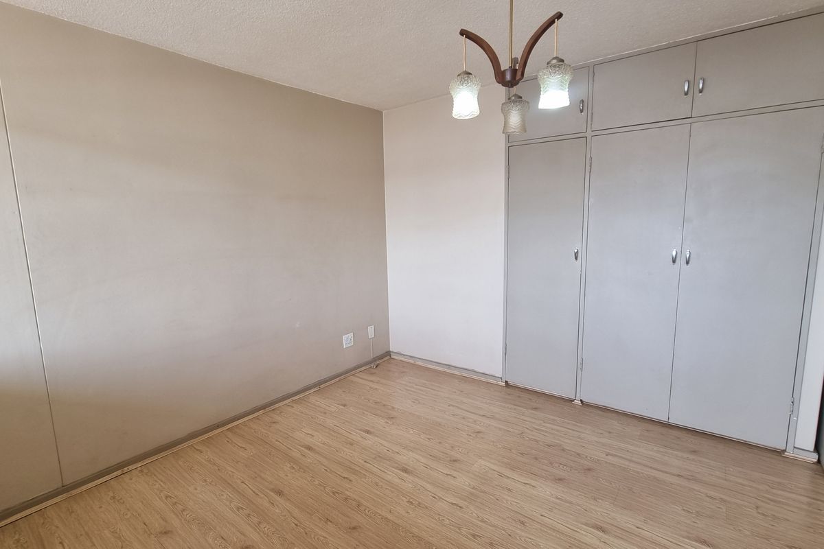 An empty bedroom featuring laminate flooring and built-in cupboards, offering a neutral canvas for personalization.